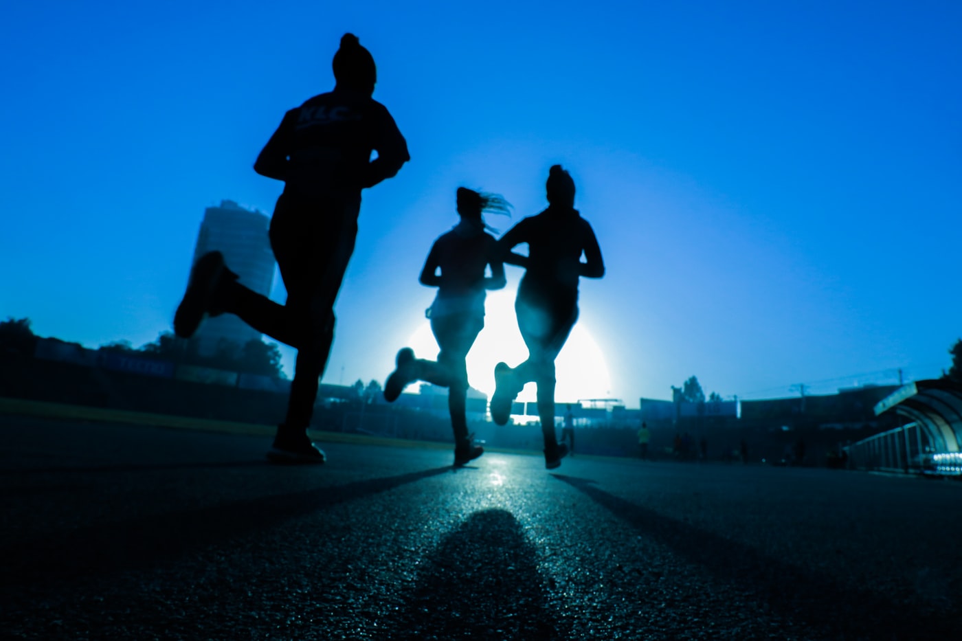 Runners in silhouette on a dusk track
